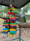 Parrot interacting with a colorful wooden toy in a cage.